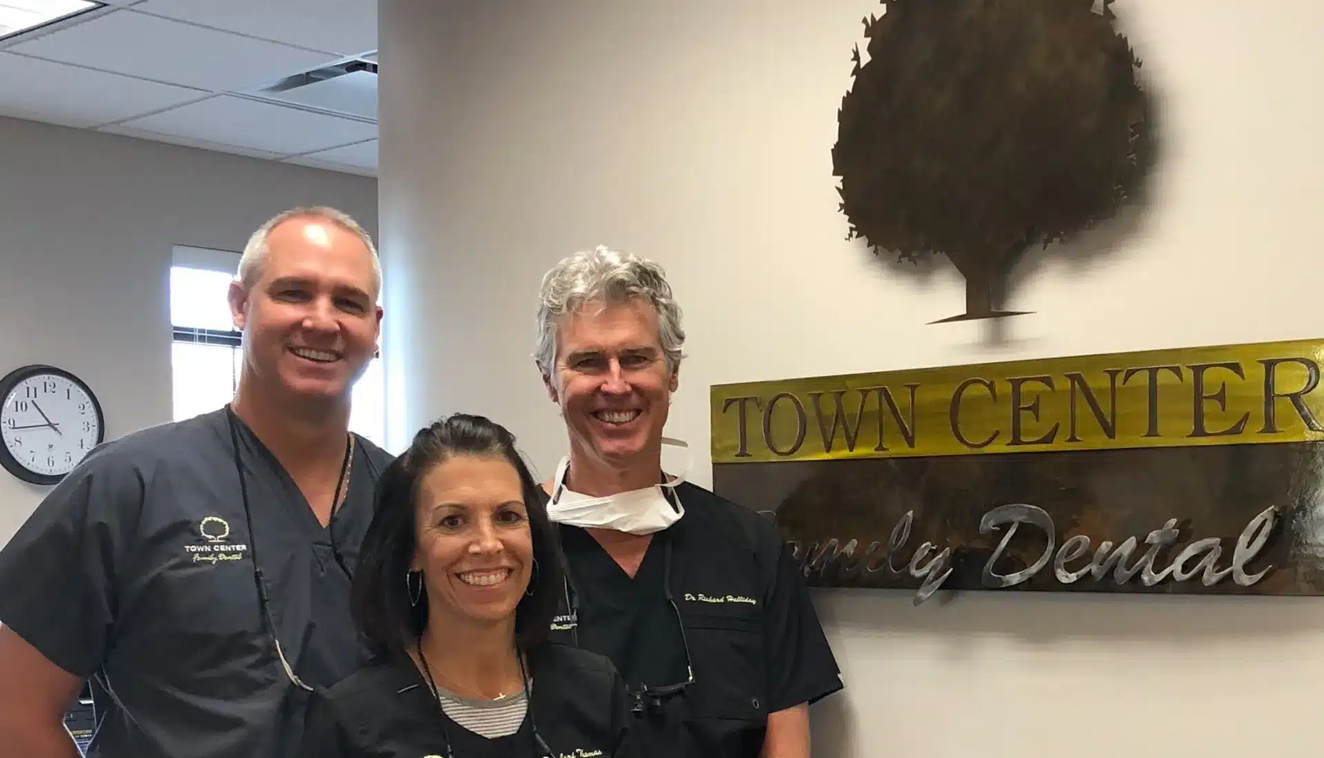 Four dental staff members smile together in front of Town Center Family Dental office signage.