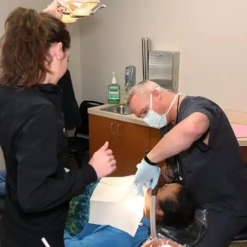 Dental hygienist examining patient's teeth in clinical treatment room at Town Center Family Dental.