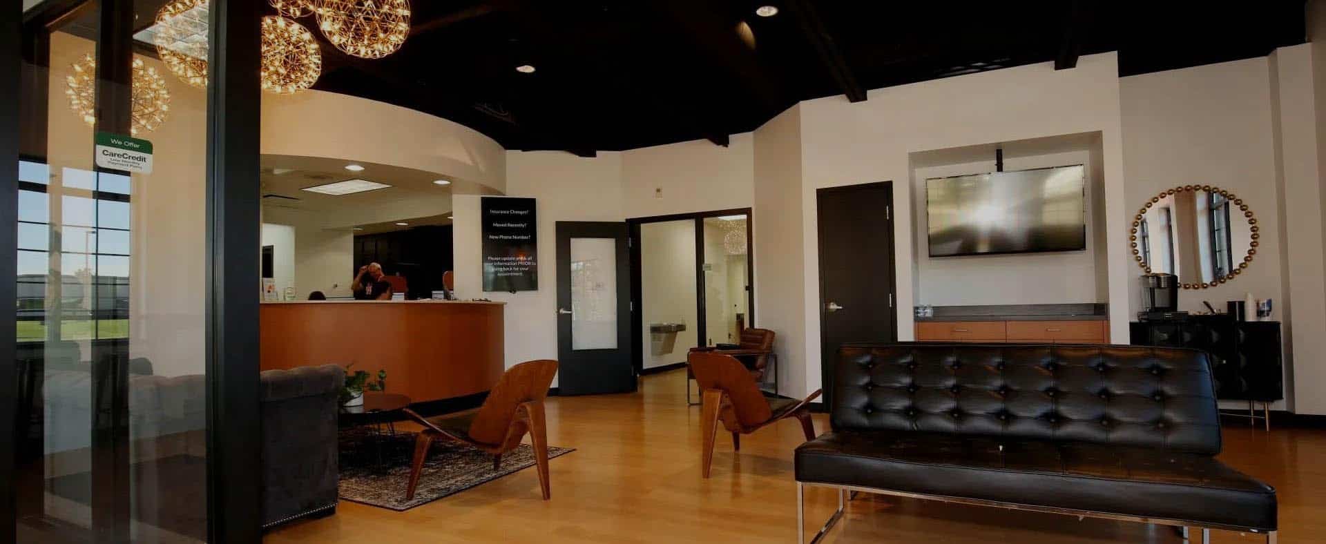 Modern dental office reception and waiting area with wood flooring and contemporary furniture.