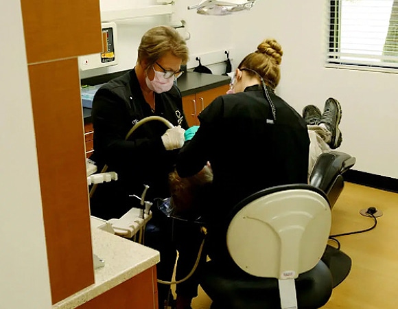 Dentist examining patient's teeth in dental office treatment room.