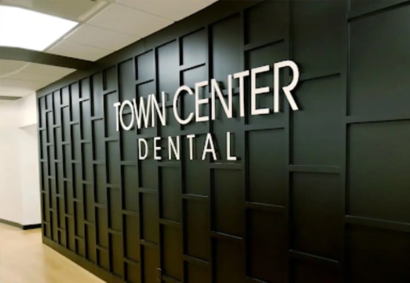 Town Center Dental entrance sign on dark paneled wall in modern dental office hallway
