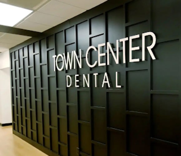 Town Center Dental entrance sign on dark paneled wall in modern office building hallway.