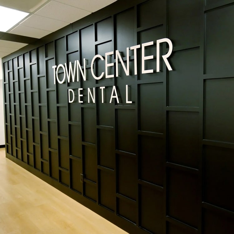 Town Center Dental office entrance with illuminated signage on dark paneled wall in modern hallway.