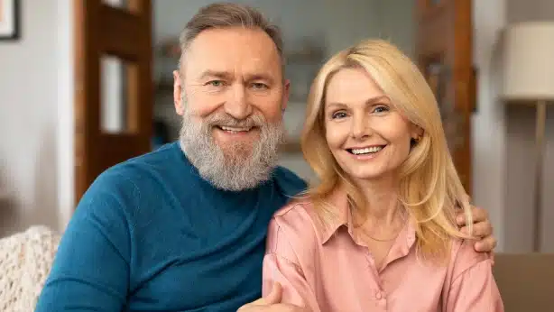 Two smiling adults posing together in a dental office interior setting.