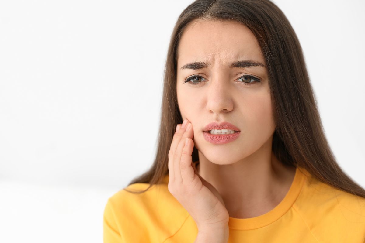Woman experiencing toothache while touching cheek