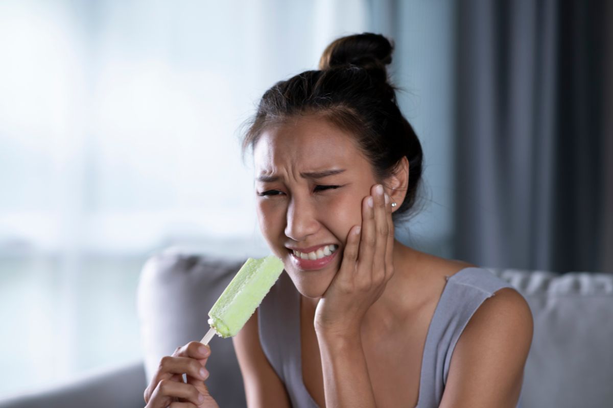 Woman experiencing tooth sensitivity from ice cream