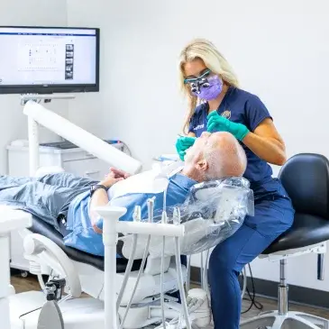 Dentist examining patient's teeth during dental implant consultation in Flint office.
