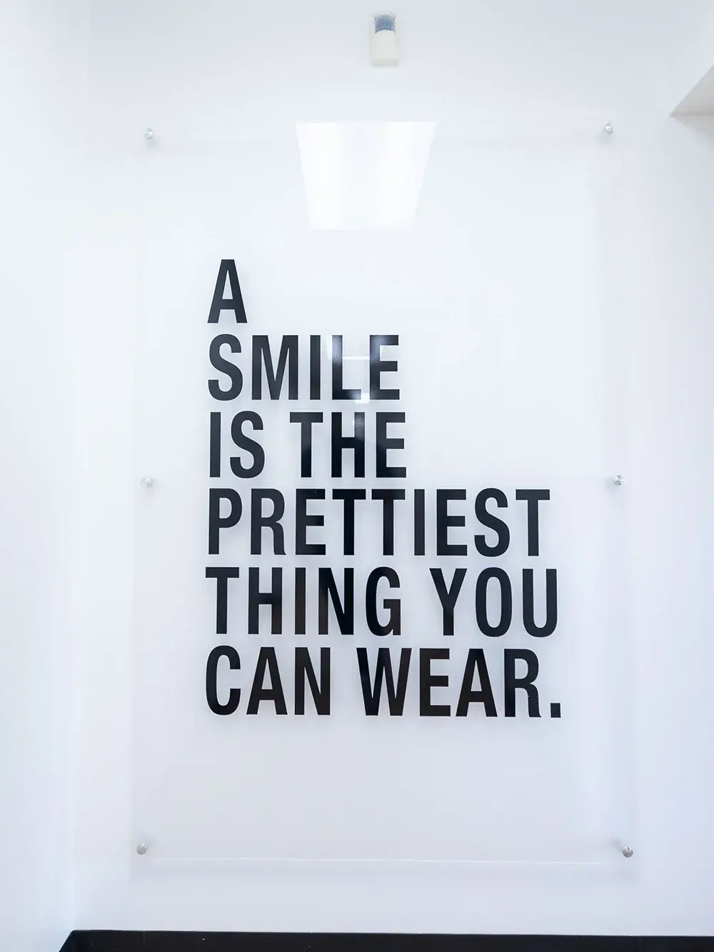 Inspirational wall decor in a dental office reading "A smile is the prettiest thing you can wear.