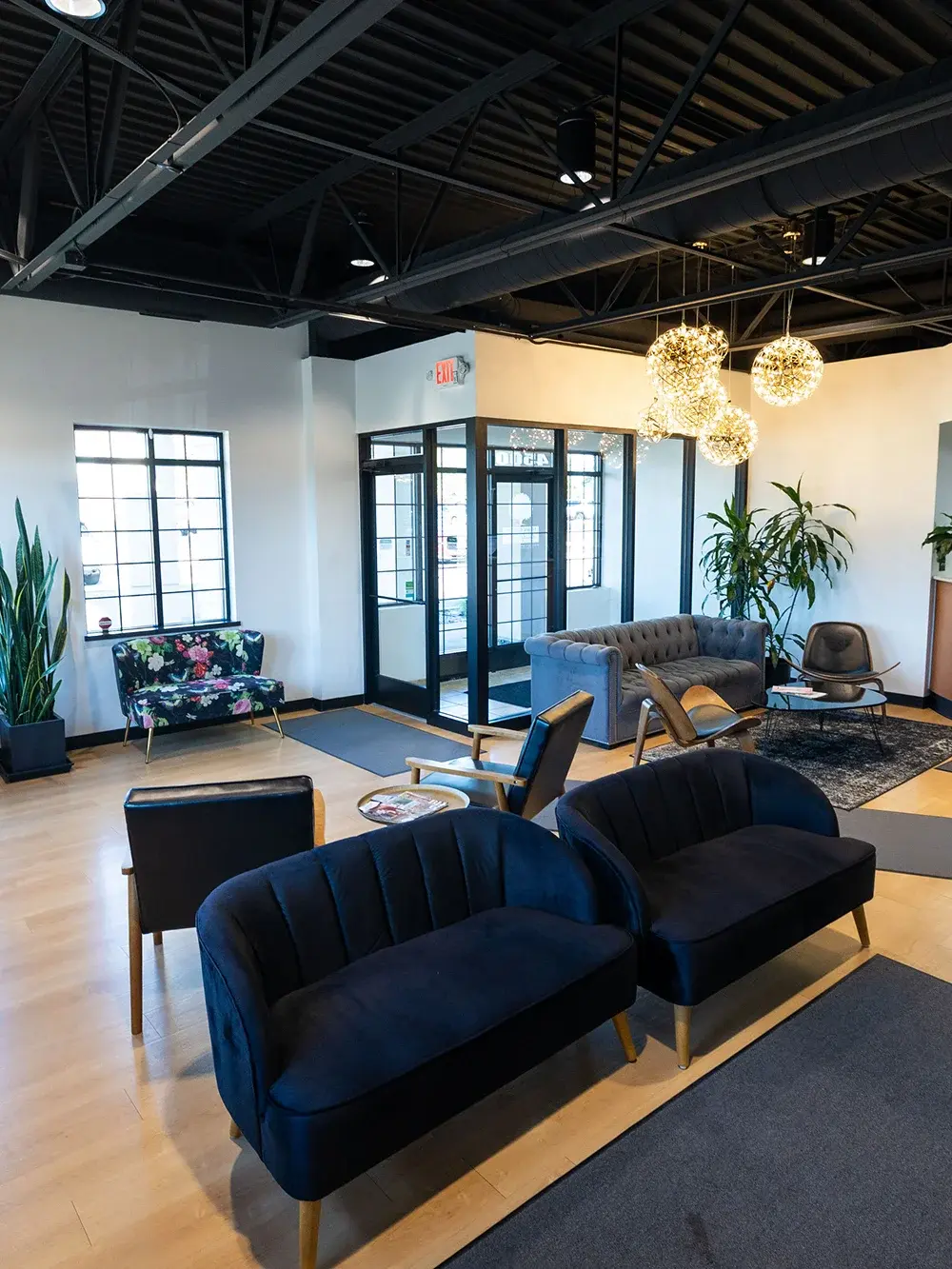Modern dental office waiting room with blue velvet seating and contemporary lighting fixtures.