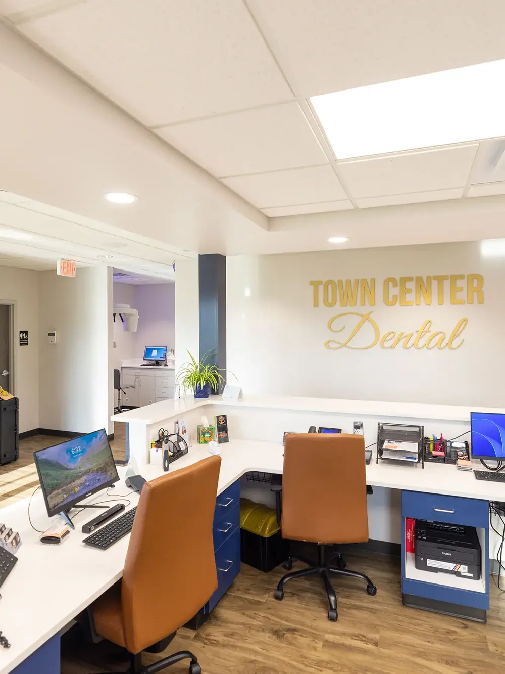 Town Center Dental reception desk with modern workspace, orange chairs, and branding on wall.