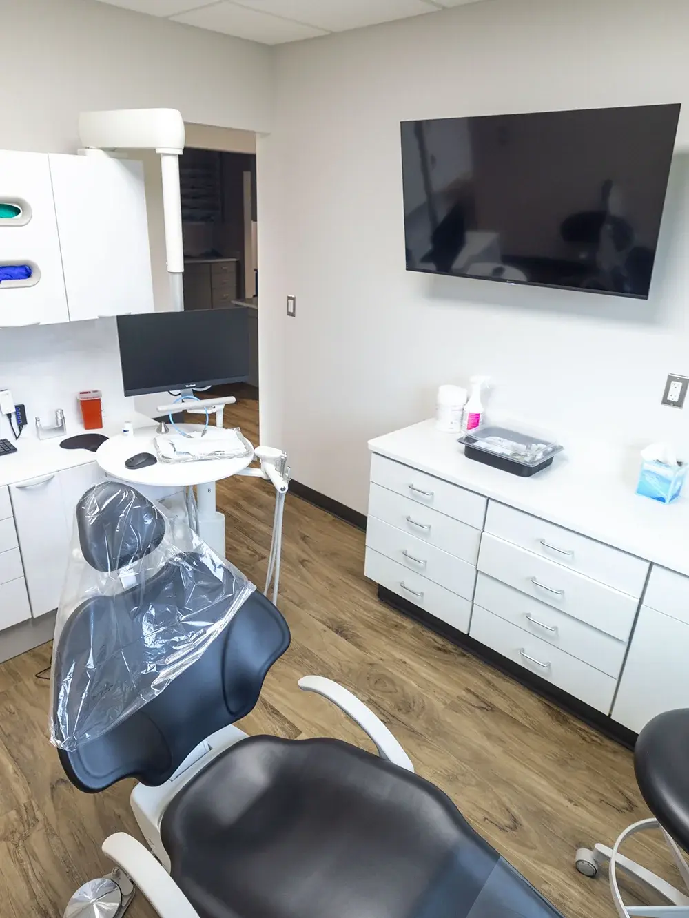 Modern dental treatment room with chair, monitor, and storage cabinets in Flint, MI.