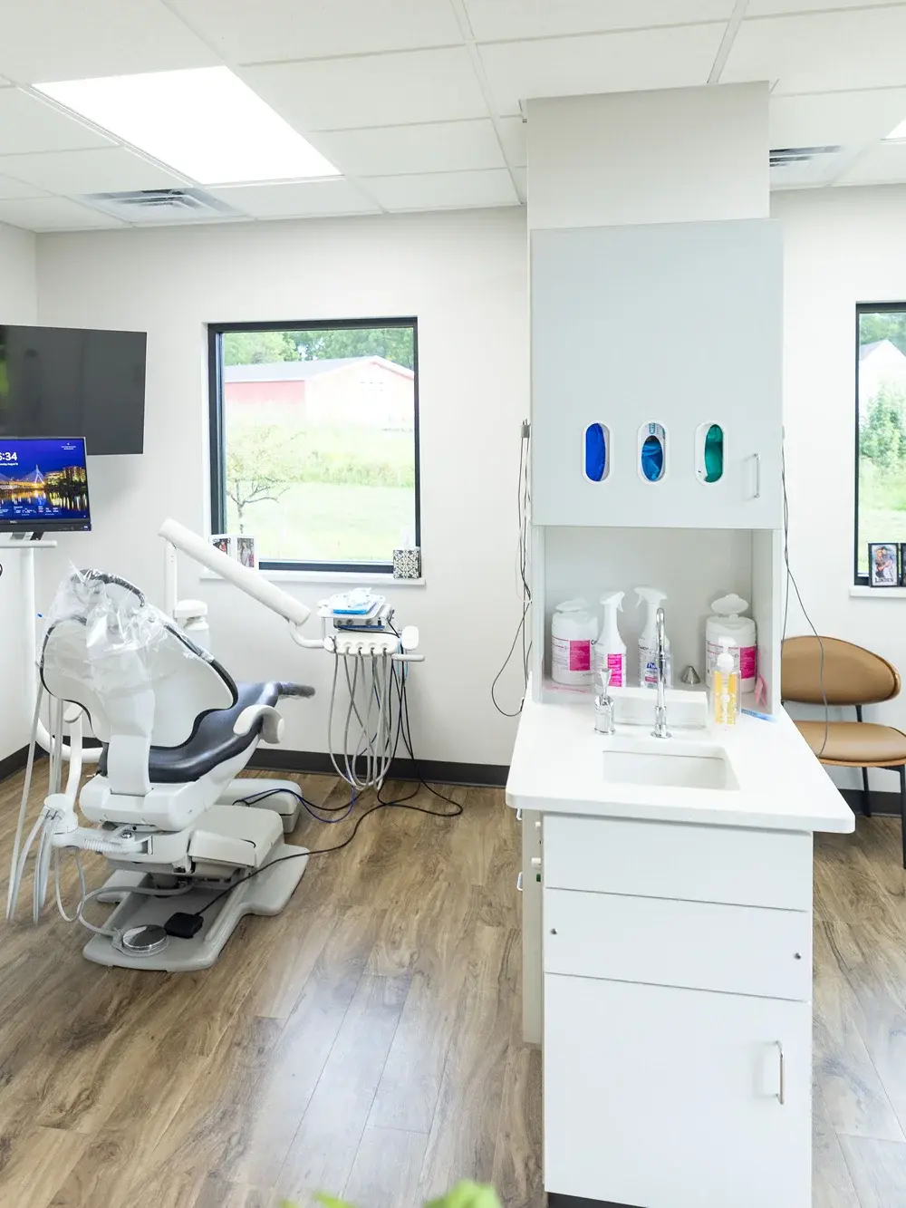 Modern dental treatment room with white cabinetry, dental chair, and sink at Flint dental practice.
