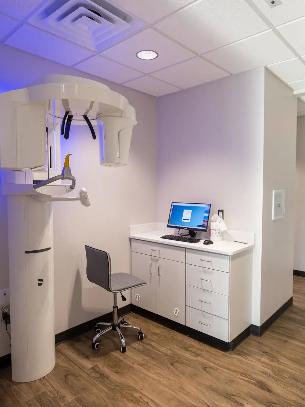 Modern dental X-ray imaging room with panoramic scanner and consultation workstation in Flint.