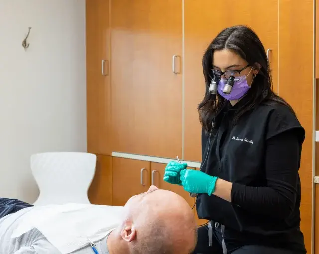 Dr. Summer Dentist performing dental treatment on patient in Flint, Michigan office.