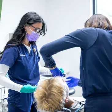 Dental hygienist examining patient's teeth during preventative care appointment in Flint.