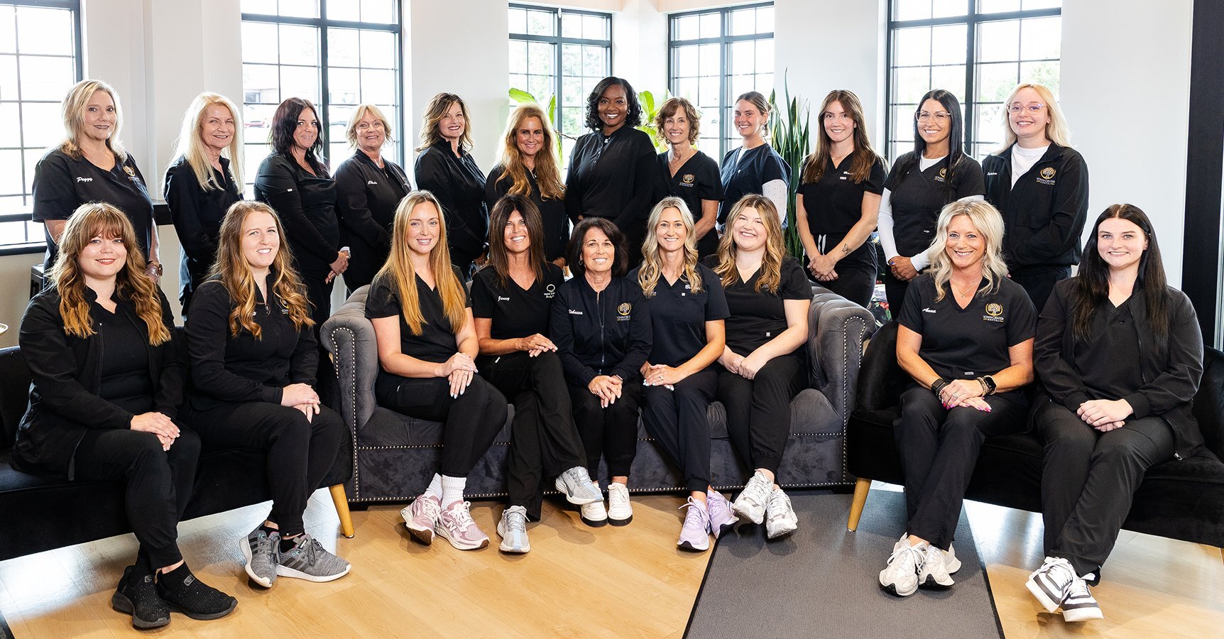 Dental team of women in black uniforms posing together at Town Center Flint practice.